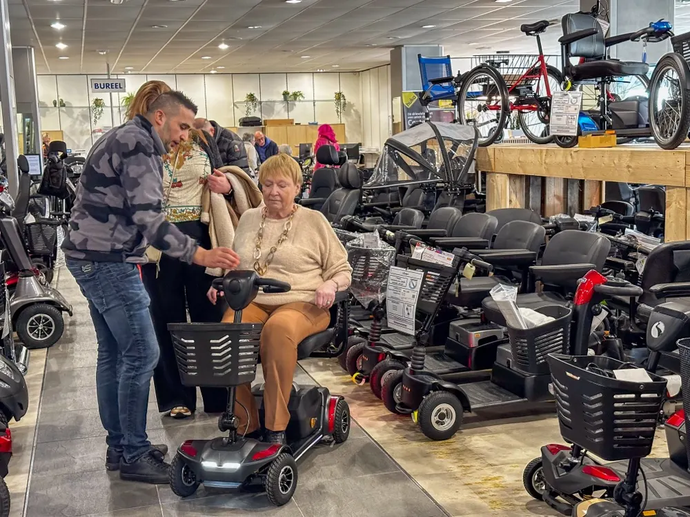 Klant test een scootmobiel met hulp van een medewerker